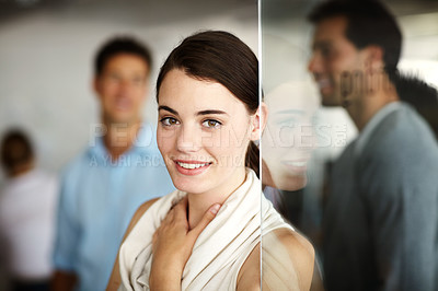 Buy stock photo Portrait of an attractive young employee standing wioth her colleagues blurred in the background