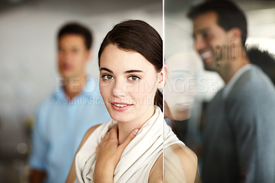 Buy stock photo Portrait of an attractive young employee standing wioth her colleagues blurred in the background