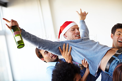 Buy stock photo Christmas, party and drunk worker with an alcohol bottle lifted by crazy employees to celebrate in a office building. Friends, freedom and happy people carry a funny ot excited man in a company event