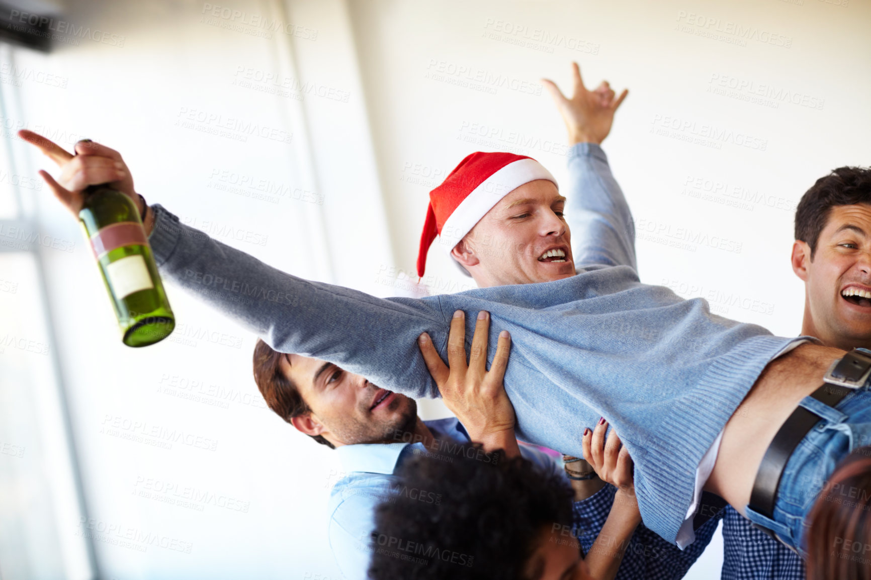 Buy stock photo Christmas, party and drunk worker with an alcohol bottle lifted by crazy employees to celebrate in a office building. Friends, freedom and happy people carry a funny ot excited man in a company event