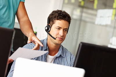 Buy stock photo A handsome young man sitting at his desk and being handed a document