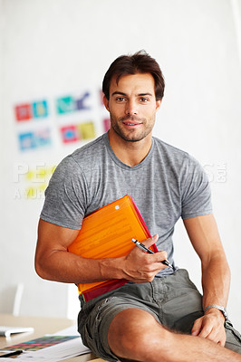 Buy stock photo Portrait of a handsome man sitting on an office desk with folder under his arm and pen in hand