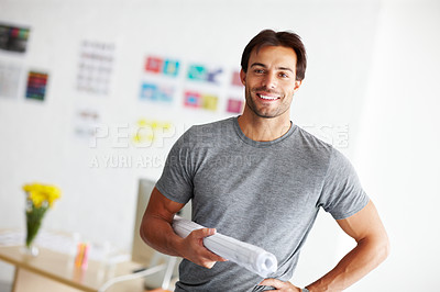 Buy stock photo Portrait of a handsome young man standing in his office with design plans under is arm and hand on his hip 