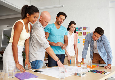 Buy stock photo A group of designers gathered together around an office table to discuss their plans