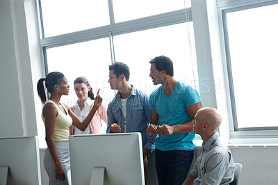 Buy stock photo A group of colleagues standing in a office and engaging in an intense conversation