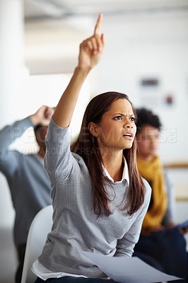 Buy stock photo A beautiful young woman sitting with her hand raised to ask a question 