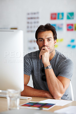 Buy stock photo A handsome young man sitting in front of his computer looking pensive
