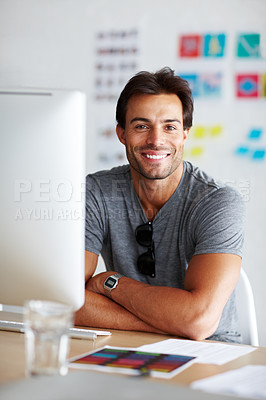 Buy stock photo A handsome young man sitting and smiling in front of his computer