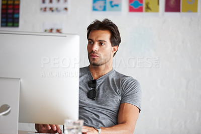 Buy stock photo A handsome young man sitting in front of his computer
