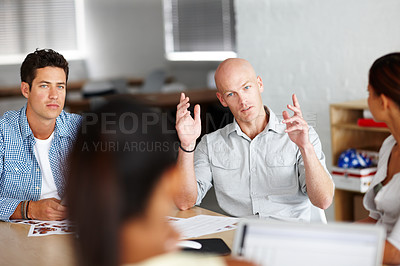 Buy stock photo A young man making his point in a meeting with colleagues