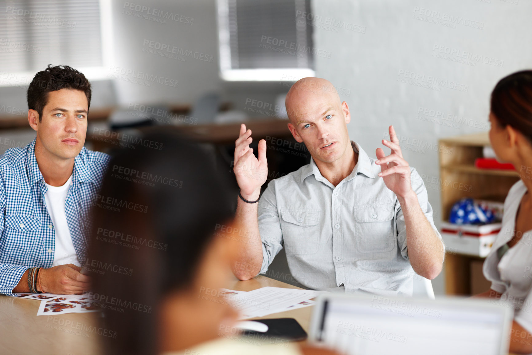 Buy stock photo A young man making his point in a meeting with colleagues