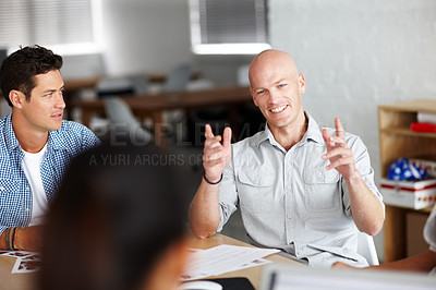 Buy stock photo A young man giving his oppinion in a meeting with colleagues