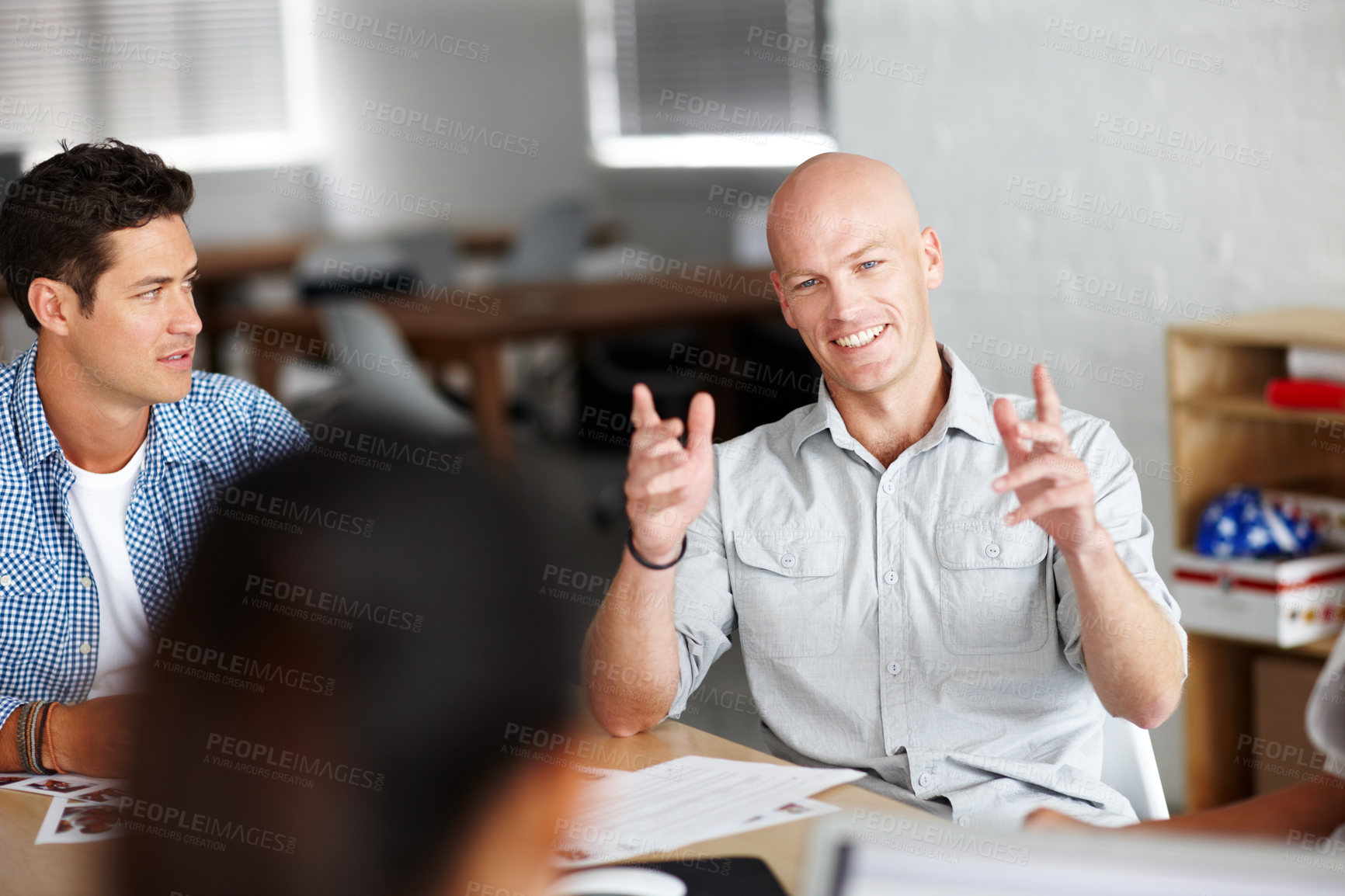 Buy stock photo A young man giving his oppinion in a meeting with colleagues