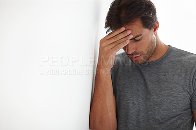 Buy stock photo Shot of a depressed-looking young man with his head in his hand with copyspace