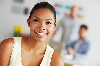 Buy stock photo Portrait of a confident young african american designer with her colleagues in the distanc ebehind her