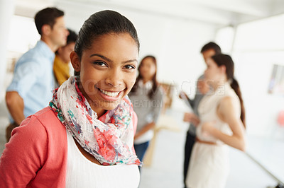 Buy stock photo Closeup portrait of an attractive young designer smiling for the camera with her coworkers behind her