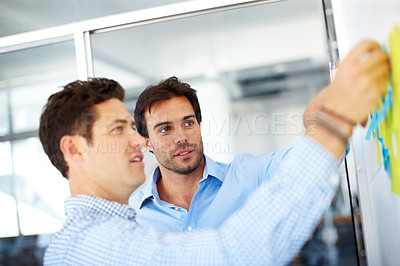 Buy stock photo Two male designers making notes and brainstorming together