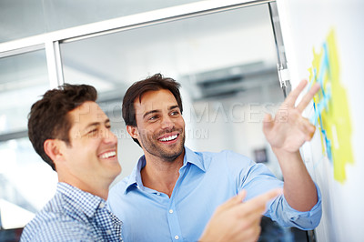 Buy stock photo Two male designers making notes and brainstorming together