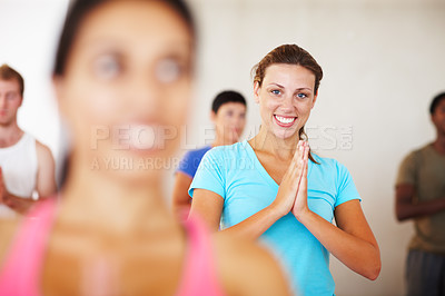 Buy stock photo A young woman smiling while doing a yoga pose in gym class