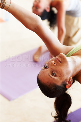 Buy stock photo Closeup of a young woman doing a backwards stretch with a group of people in yoga class