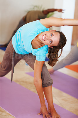 Buy stock photo Portrait of an attractive woman stretching sideways and smiling at the camera during yoga class
