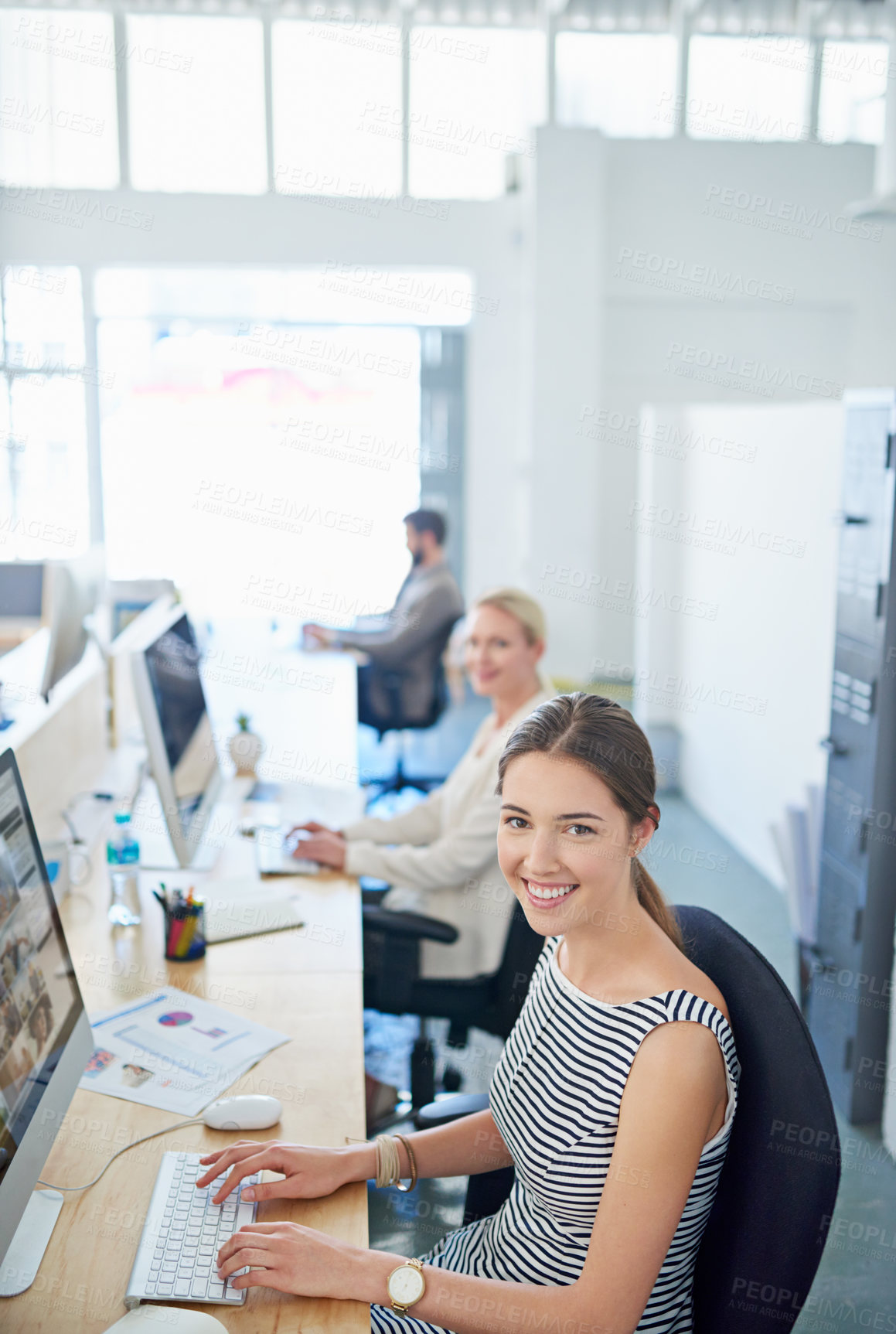Buy stock photo Portrait of a young office worker sitting at her workstation in an office