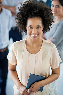 Buy stock photo Portrait of a smiling young office worker standing in an office with colleagues in the background