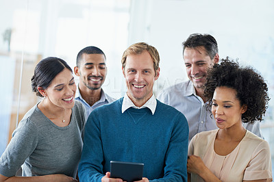 Buy stock photo Shot of a group of diverse colleagues using a digital tablet while standing in an office
