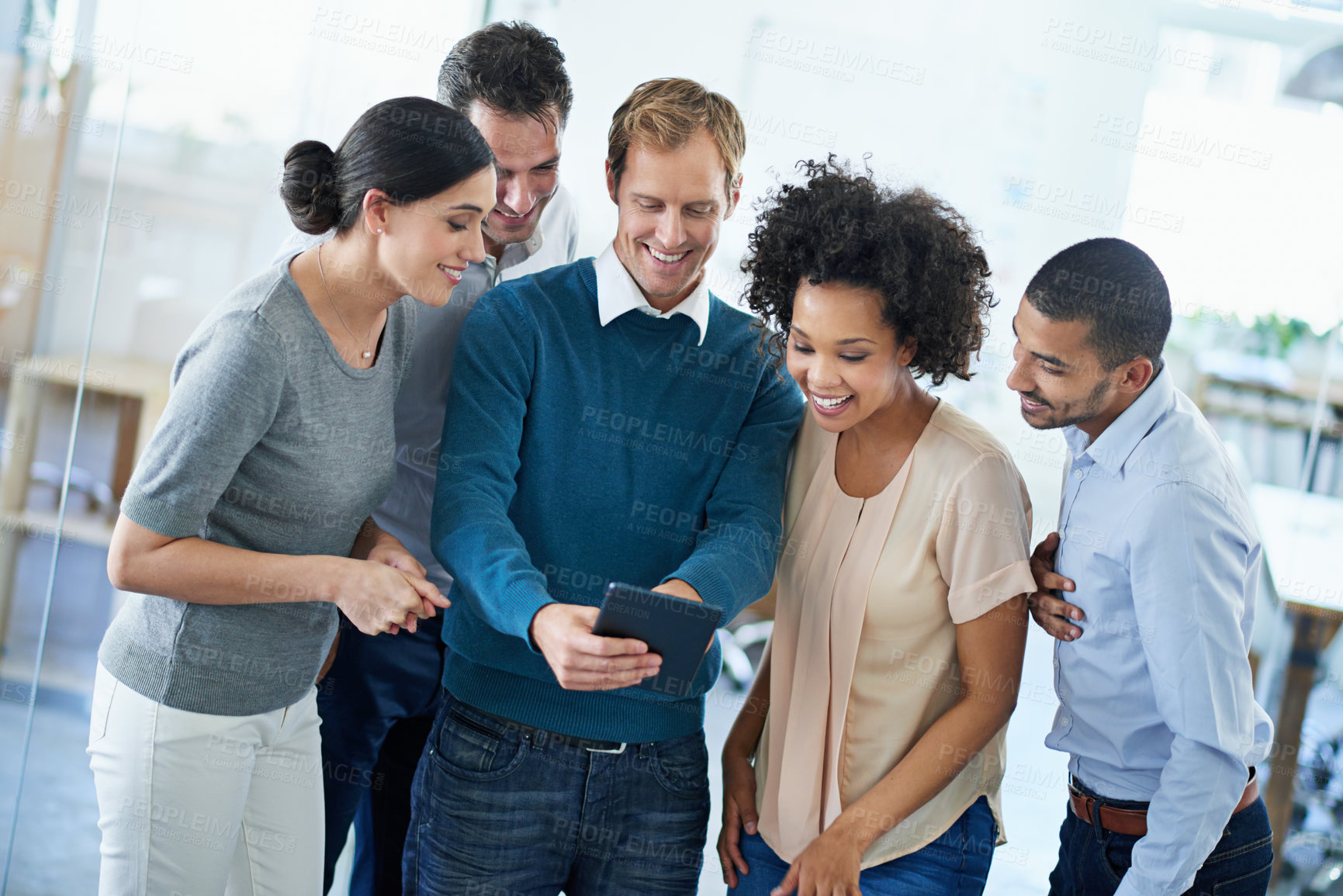 Buy stock photo Shot of a group of diverse colleagues using a digital tablet while standing in an office