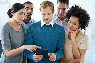 Buy stock photo Shot of a group of diverse colleagues using a digital tablet while standing in an office