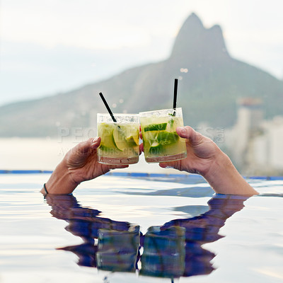 Buy stock photo Cropped shot of two people toasting in a pool with a view