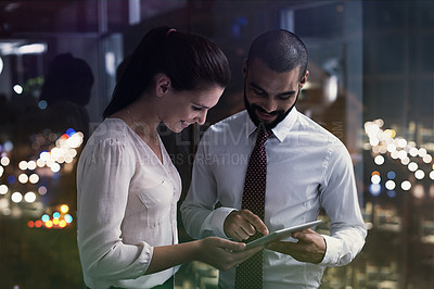 Buy stock photo Shot of two businesspeople working with a digital tablet late at night. Real life businesspeople shot on location. Since these locations are the real thing, and not shot in an 