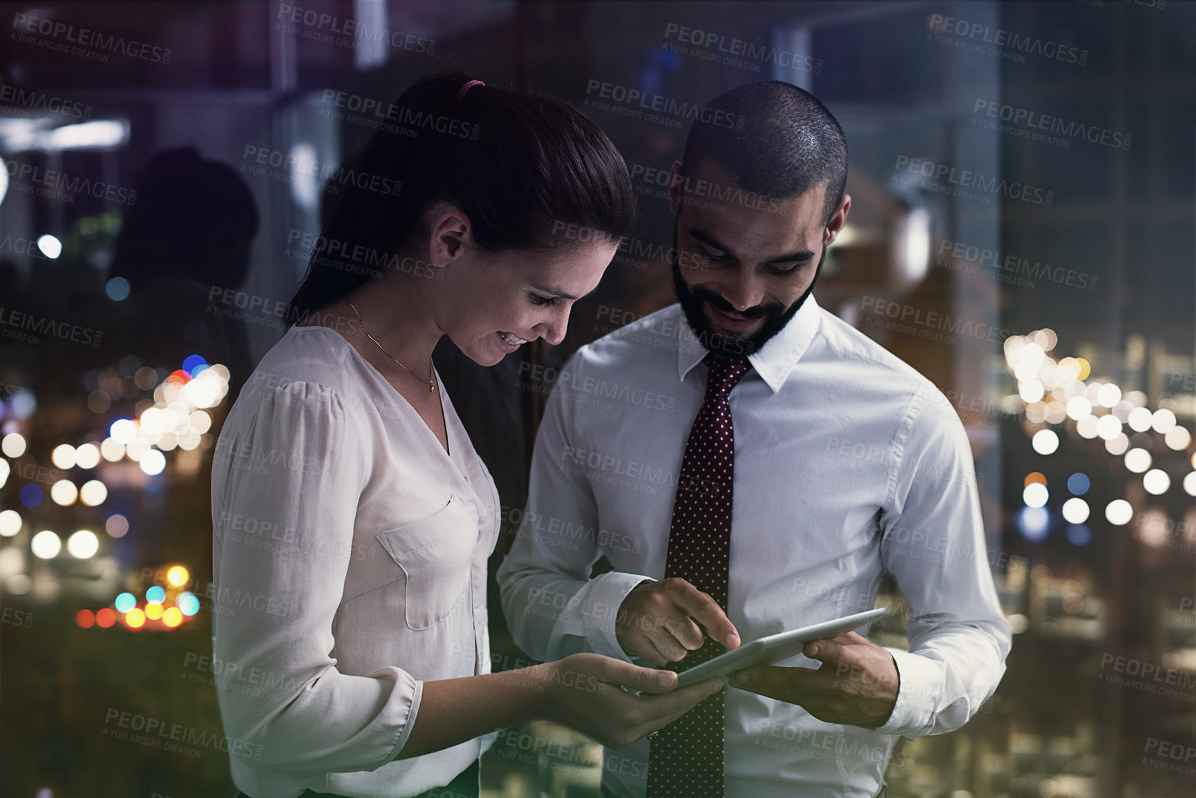 Buy stock photo Shot of two businesspeople working with a digital tablet late at night. Real life businesspeople shot on location. Since these locations are the real thing, and not shot in an 