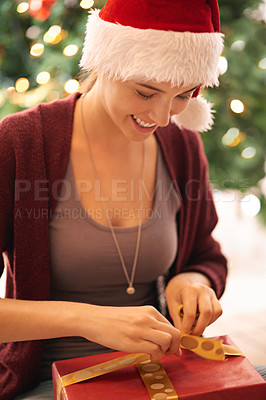 Buy stock photo Christmas, present and happy young woman opening a box by the tree in celebration of holidays. Happiness, excited and girl from Canada with xmas gift wearing festive, fun and traditional hat at home.