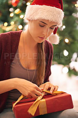 Buy stock photo Christmas, gift and woman on floor in living room on xmas eve, content and calm while wrapping ribbon. Festive, holiday and girl open present box in celebration of traditional holiday in her home