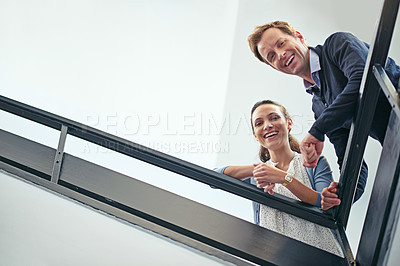 Buy stock photo Low angle portrait of two coworkers leaning on a stairwell bannister