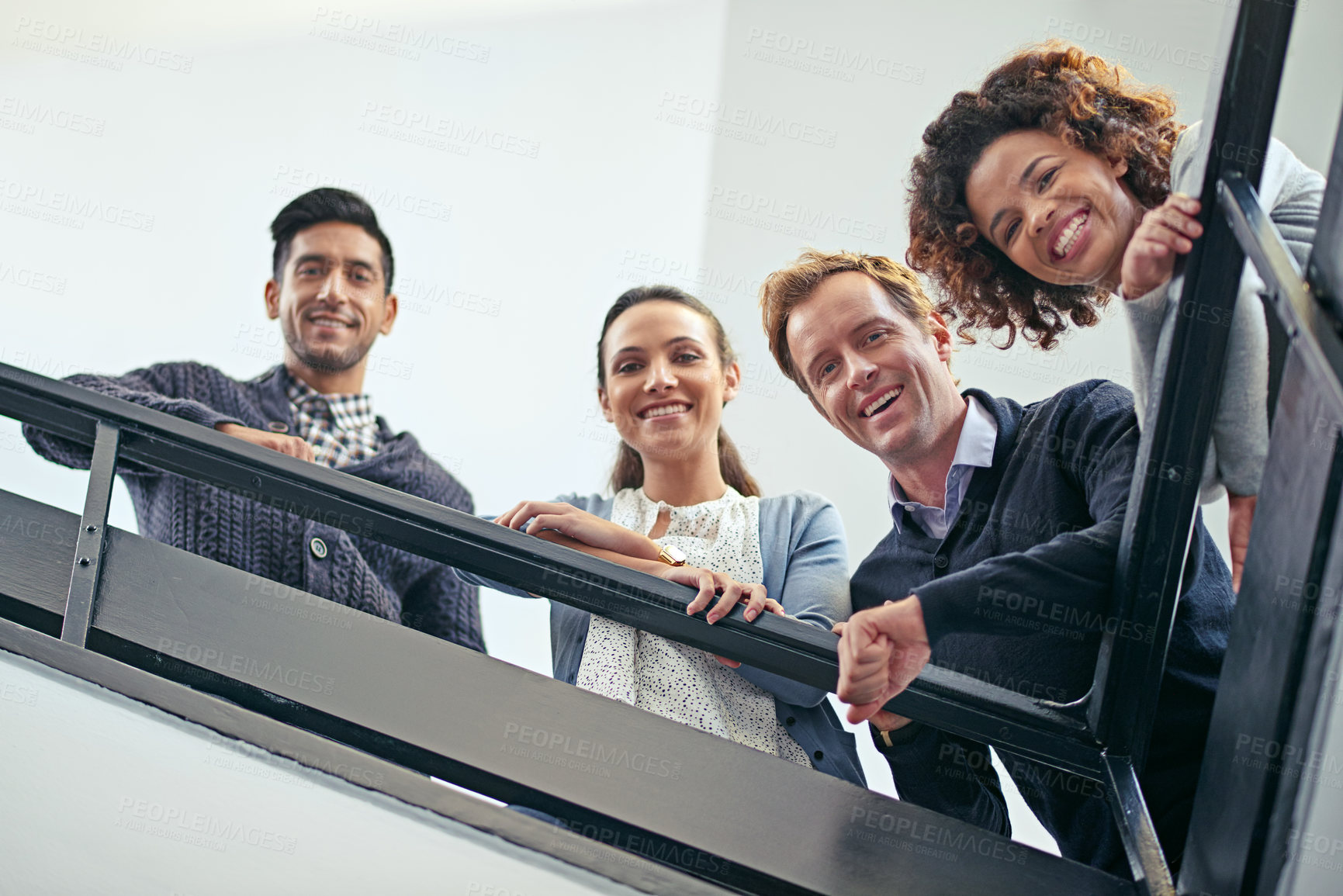 Buy stock photo Low angle portrait of a group of coworkers leaning on a stairwell bannister