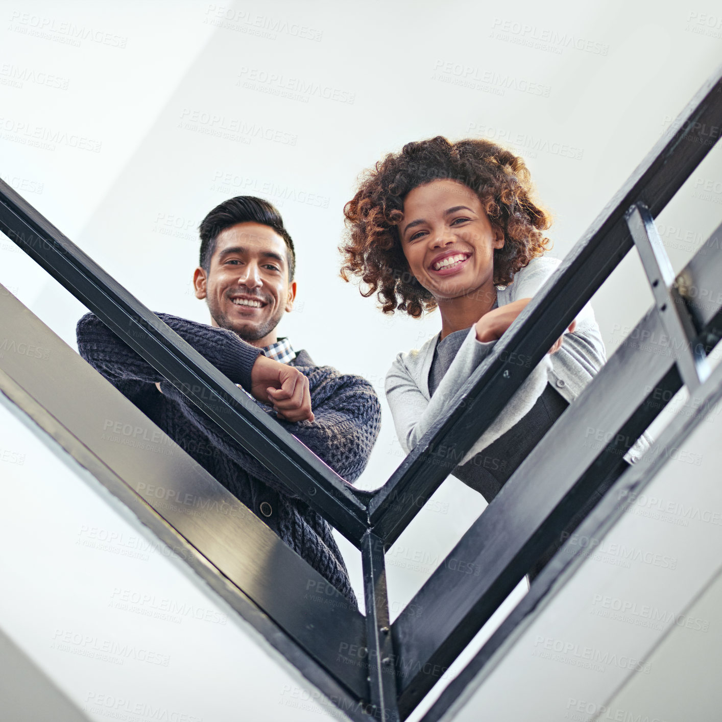 Buy stock photo Low angle portrait of two coworkers leaning on a stairwell bannister