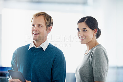 Buy stock photo Shot of two smiling colleagues standing in an office