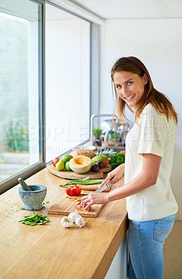 Buy stock photo Shot of an attractive young woman chopping vegetables in a kitchen