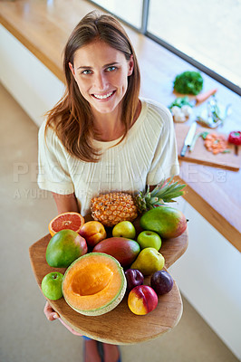 Buy stock photo Shot of an attractive young woman holding a cutting board full of fresh furit