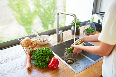 Buy stock photo Cropped shot of a woman washing vegetables in a kitchen sink