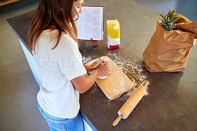 Buy stock photo A young woman kneading dough in her kitchen
