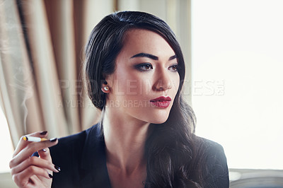 Buy stock photo Shot of a woman smoking a cigarette in a luxurious setting wearing classicly elegant attire