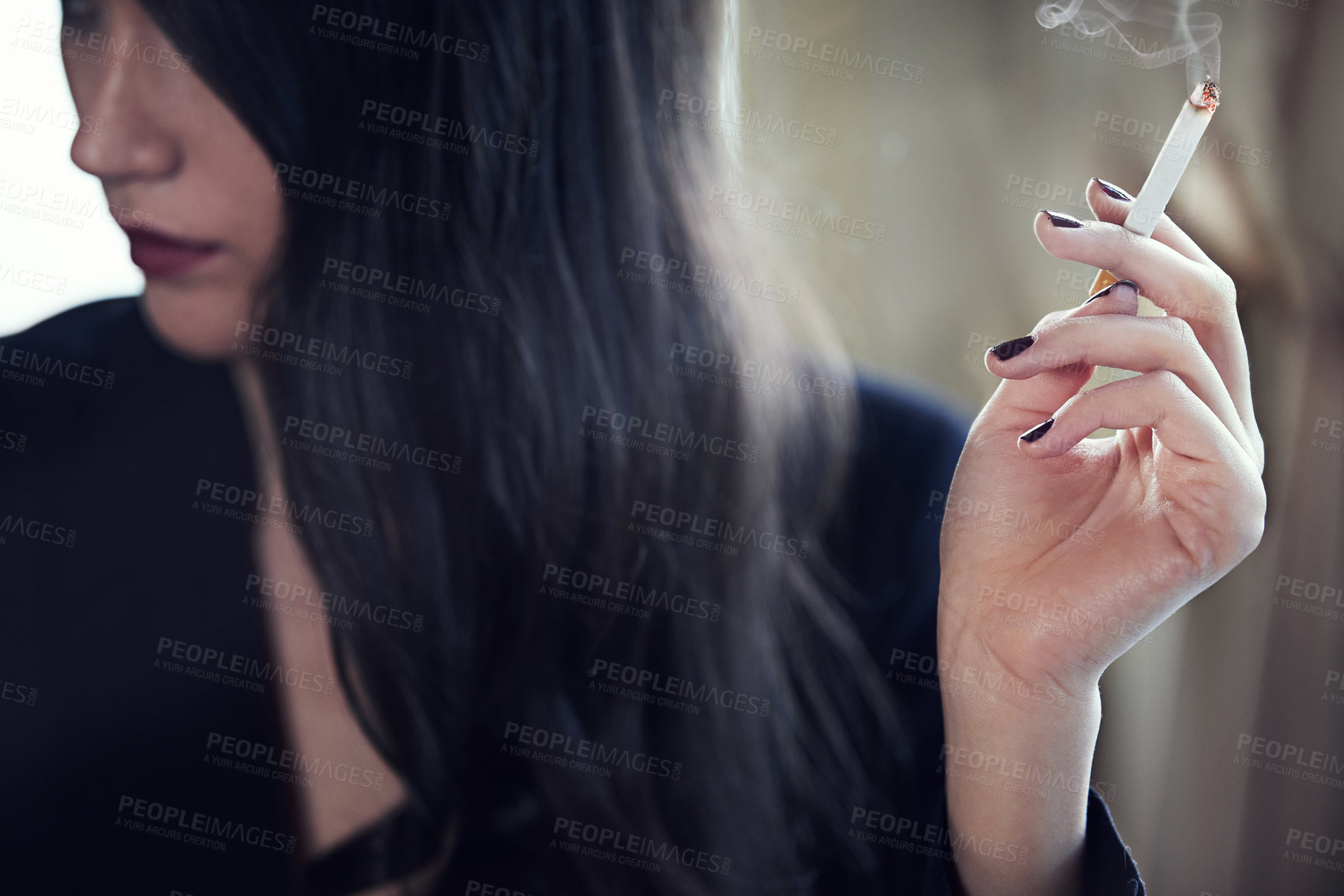 Buy stock photo Cropped shot of an elegant young woman smoking