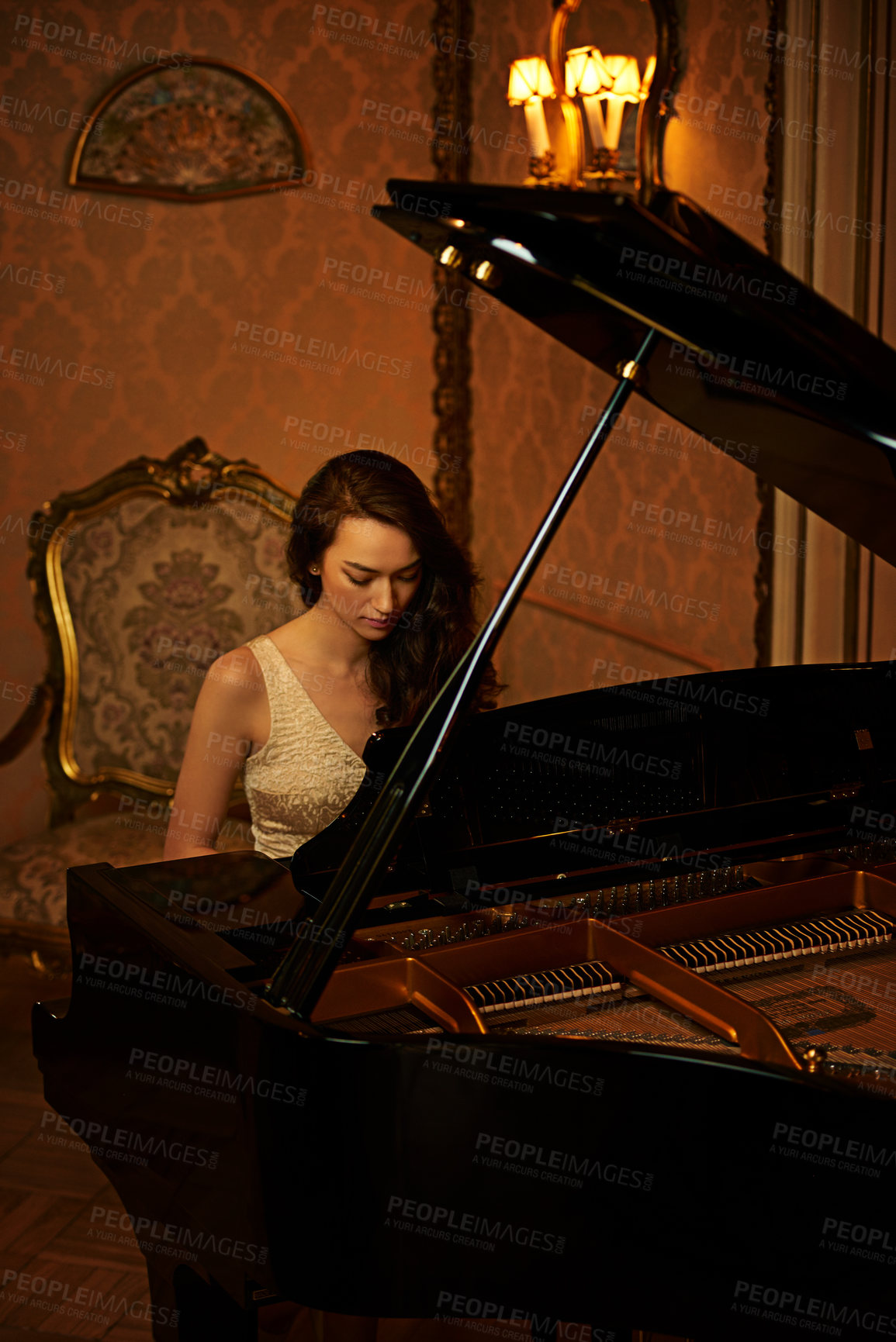 Buy stock photo Shot of a beautiful young woman playing the piano