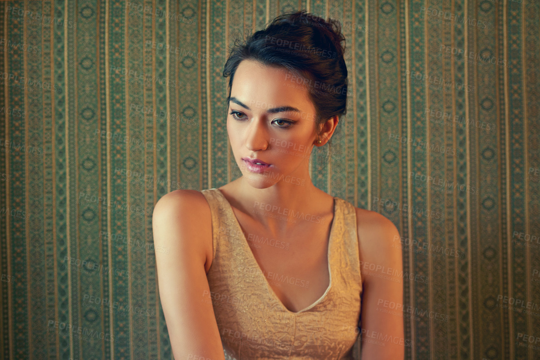 Buy stock photo Shot of a beautiful young woman dressed elegantly in a green wallpapered room