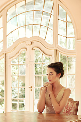 Buy stock photo Shot of a beautiful young woman sitting at a table in her elegant home 
