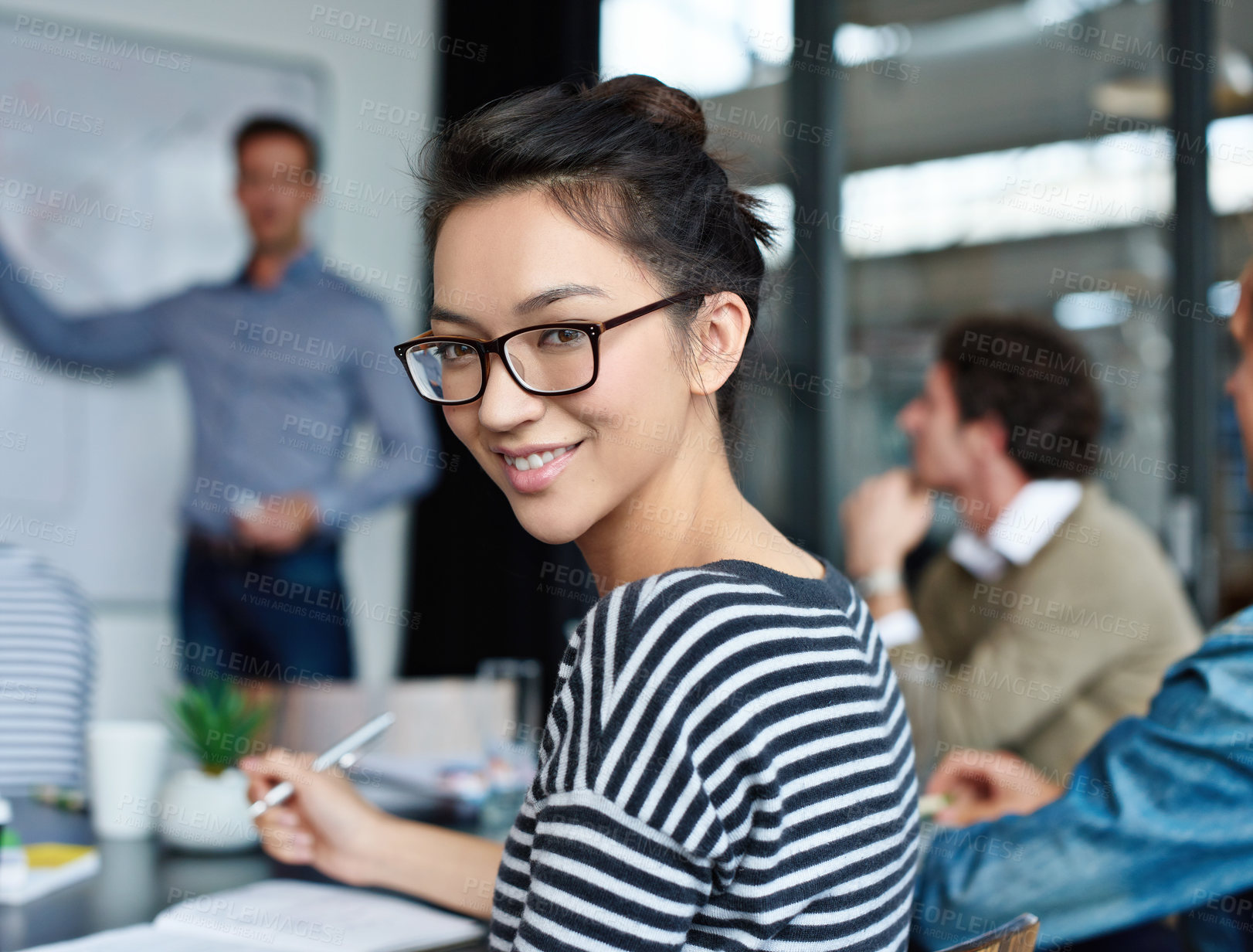 Buy stock photo Portrait of an attractive young woman sitting in an office with colleagues in the background