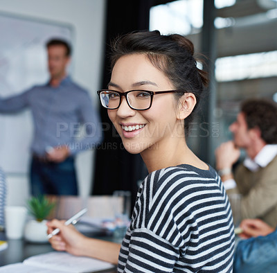 Buy stock photo Portrait of an attractive young woman sitting in an office with colleagues in the background